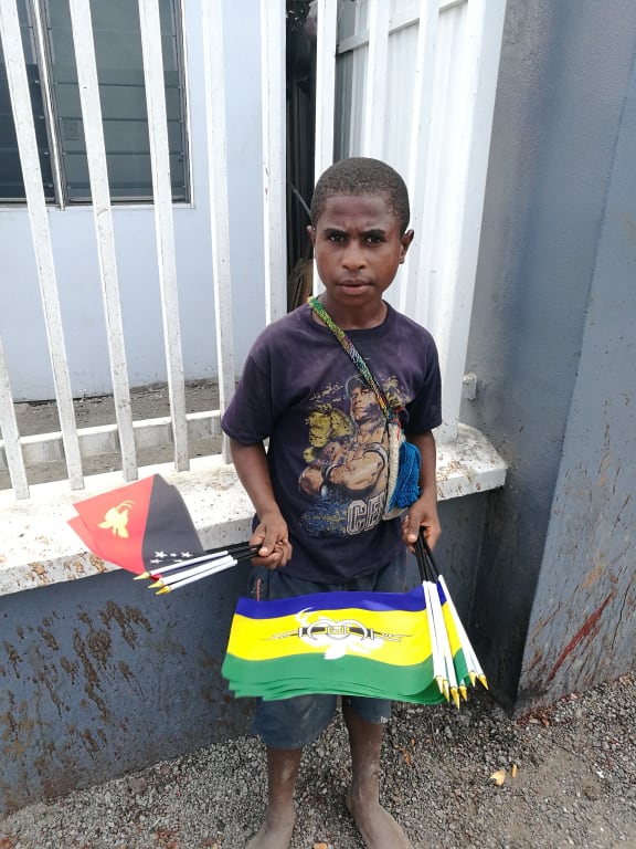 Boy holding Papua New Guinea national and Morobe provincial flags.