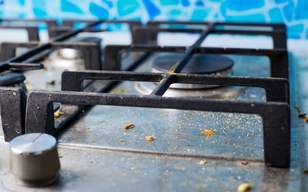 Gas stove top with food leftovers. Unclean steel kitchen cooktop with greasy spots. Spring-cleaning, remove kitchen old fat stains, fry spots, oil splatters and burned-on bits.
