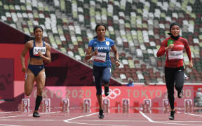 Iran's Fasihi Farzaneh, right, runs to first place ahead of  third-placed Kuwait's Mudhawi Alshammari, centre, and Guam's Regine Kate Tugade, left, in the women's 100m heats during the Tokyo 2020 Olympic Games at the Olympic Stadium in Tokyo on 30 July 2021.