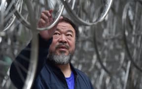 Chinese artist Ai Weiwei touches his sculpture "Forever" at the base of the the "Gherkin" tower in London.
