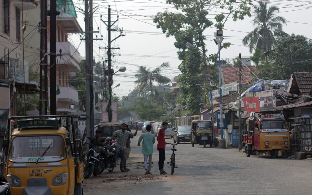 Street in Kerala town with tangled overhead wires,, trees and tuk tuks