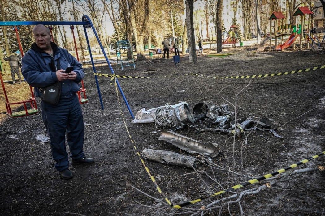 A man stands next to remains of a missile in the eastern Ukraine city of Kharkiv on February 24, 2022, as Russian armed forces launched a military invasion of Ukraine.