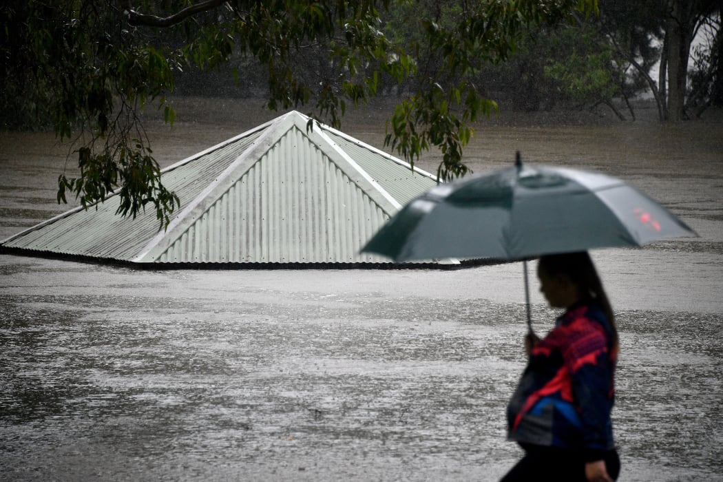 A woman walks past a flooded park along the overflowing Nepean river in Penrith on 21 March as Sydney braced for its worst flooding in decades.