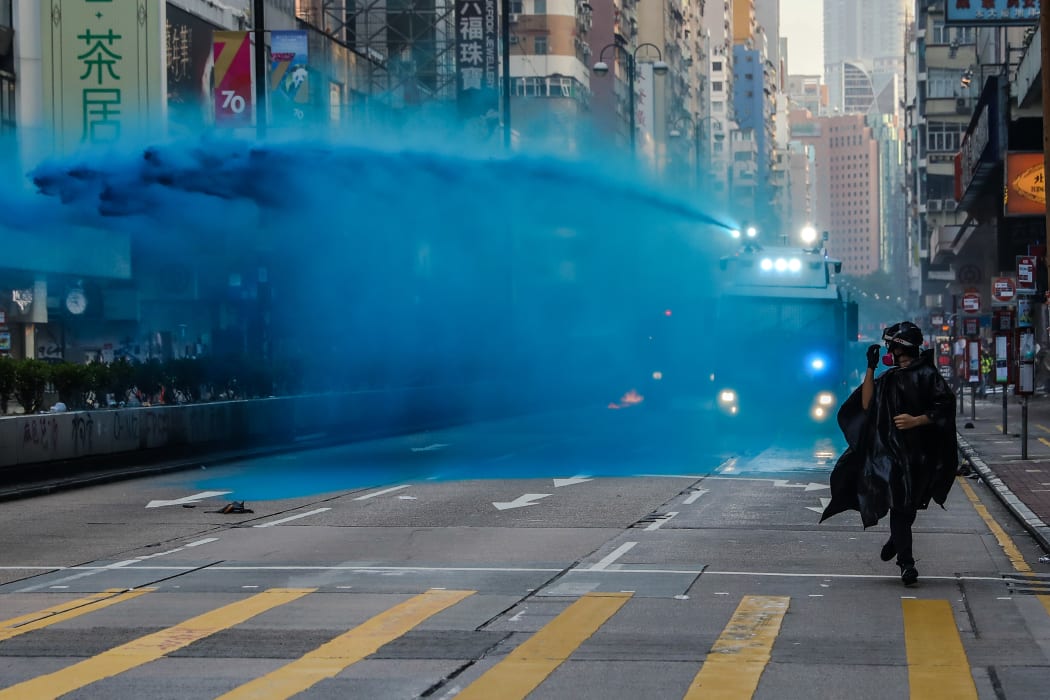 A protester runs from advancing police as they deploy a water cannon on a road in the Tsim Sha Tsui district in Hong Kong on October 20, 2019.