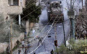 People confront an Israeli military vehicle during an Israeli army raid in the Jenin camp for Palestinian refugees in the occupied West Bank on March 7, 2023. Israeli troops killed six Palestinians.