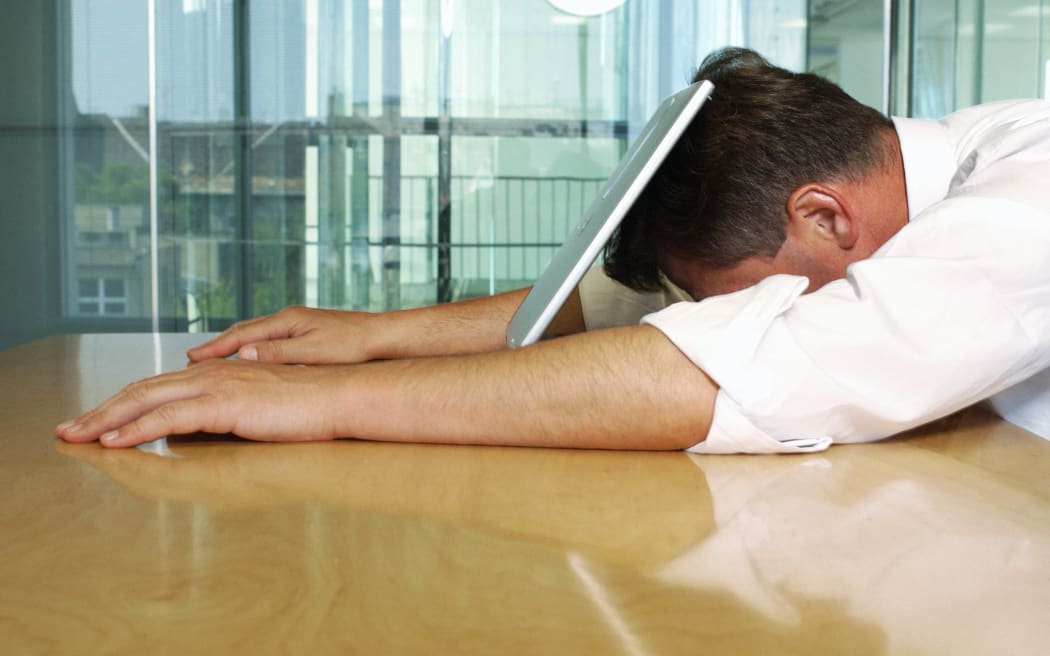 Businessman lying with face on laptop. (Photo by Téo Lannié / AltoPress / PhotoAlto via AFP)