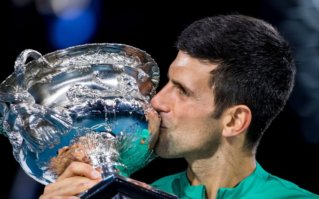 Novak Djokovic of Serbia kisses his trophy after winning the Men's Singles Final of the 2021 Australian Open