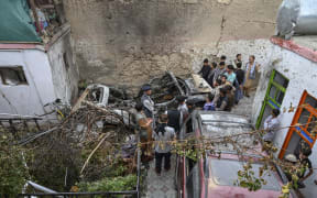 Afghan residents and family members of the victims gather next to a damaged vehicle a day after a US drone airstrike in Kabul on 30 August 2021.