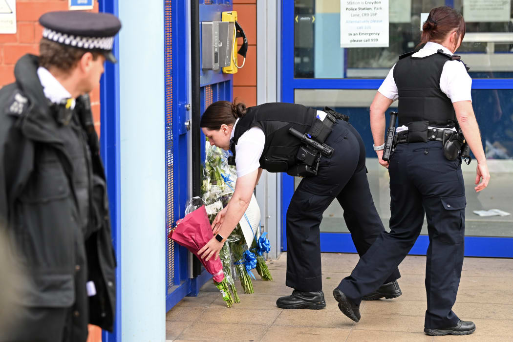 Police officers wearing protective face masks, pay their respects outside the Croydon Custody Centre in south London on 25 September 2020, following the shooting of a British police officer who is reported to be a NZer by a 23-year-old man being detained at the centre.