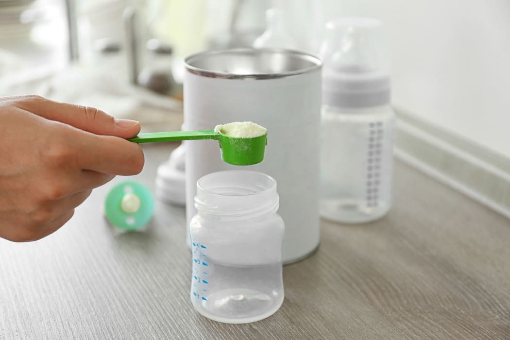 Preparing baby milk formula on wooden table closeup