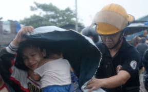 A fireman helps a mother and her family evacuate from their house in Manilla.