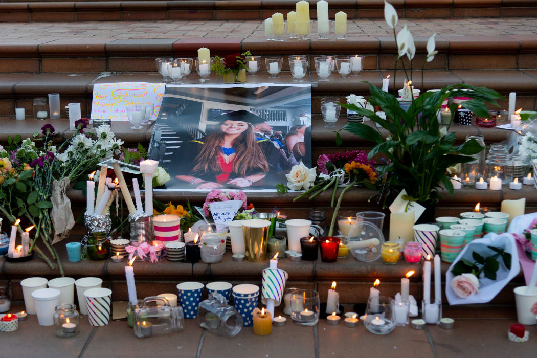 Candles and flowers are laid next to a photo of Grace Millane during the vigil at Civic Square Park in Wellington.