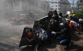 Protesters take shelter behind homemade shields after tear gas was fired during a demonstration against the military coup in Yangon.