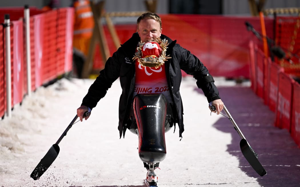 Corey Peters of New Zealand holding Shuey Rhon Rhon, mascot of the Beijing 2022 Winter Paralympic Games in his mouth, celebrates after winning the men's downhill sitting event at the Yanqing National Alpine Skiing Centre on March 5, 2022.