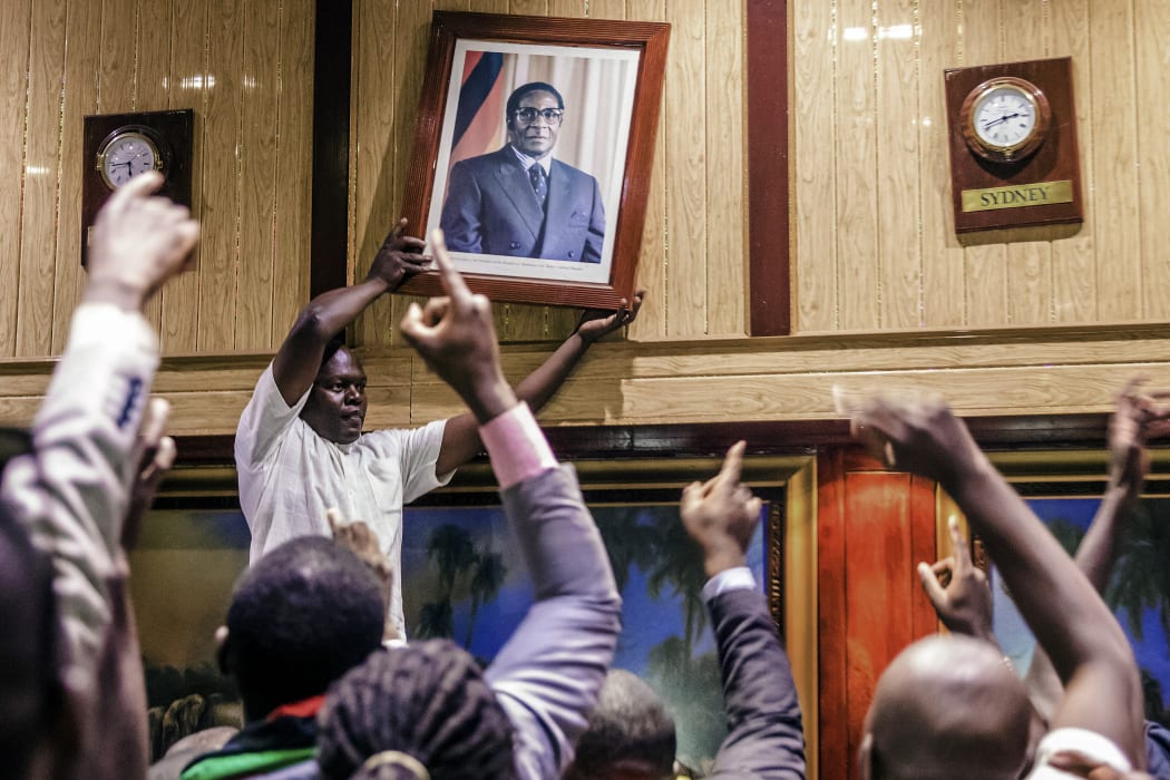 A portrait of Robert Mugabe is removed from the International Conference centre, where parliament had been sitting.