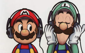 Mario and Luigi stand side by side both listening to music with their headphones.
