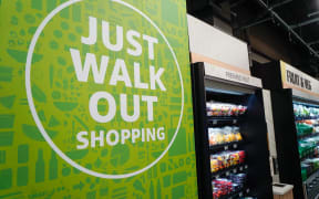 A sign reading "Just walk Out Shopping" is pictured next to a display of fresh fruit and vegetables inside Amazon's new Amazon Fresh store in Ealing, west London, on March 4, 2021. Amazon on Thursday opened the first of its Amazon Fresh grocery stores in Europe, where customers will be able to buy goods without the need to queue at a checkout. Customers will scan a QR code on their way into the store, with cameras and technology identifying the items shoppers take from the shelves. (Photo by Niklas HALLE'N / AFP)