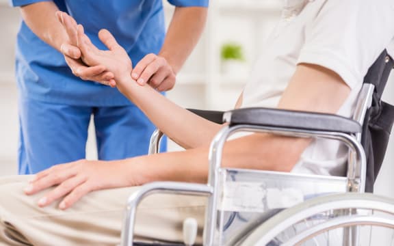 Male nurse taking pulse of senior patient at hospital.