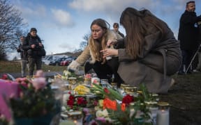 People light candles at a makeshift vigil near the adult education center Campus Risbergska school in Orebro, Sweden, on February 5, 2025 one day after a shooting there left eleven people dead. Eleven people have been killed in a shooting at an education centre in central Sweden on February 4, 2025, including the suspected assailant who was not known to police, police officials said. (Photo by Jonathan NACKSTRAND / AFP)