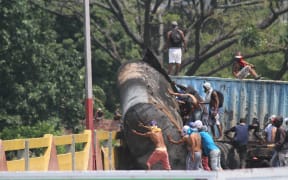 Demonstrators trying to get the trailer of a tanker that is blocking the Simon Bolivar bridge on the border between Colombia and Venezuela off the bridge.
