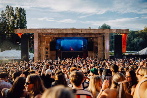 A big crowd facing an outdoor stage in the sunshine.