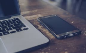 Laptop and smartphone on wooden table.