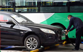 (220512) -- QINGDAO, May 12, 2022 (Xinhua) -- A driver charges an electric car at a shared electric bus charging station in Qingdao, east China's Shandong Province, May 11, 2022. Qingdao City has recently opened some electric bus charging stations to the public. Private vehicles and ride-hailing cars can share the charging facilities together with the public buses. (Xinhua/Li Ziheng) (Photo by Li Ziheng / XINHUA / Xinhua via AFP)