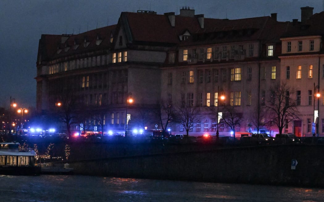 Flashing lights from emergency vehicles are seen along the bank of river Moldau at the Charles University in central Prague, 21 December 2023.