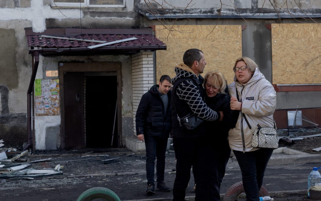 People hug a crying woman near a damaged residential building following a strike in Dobropillia, Donetsk region, on March 8, 2025, amid the Russian invasion of Ukraine. At least 11 people were killed and 30 wounded in Russian strikes on eastern Ukraine's Donetsk region late March 7, the country's emergency service said, raising the earlier death toll of four. "In the evening, Russians struck the centre of Dobropillia. At least 11 people were killed and 30 others were wounded," the service wrote in a post on Telegram, adding that at least nine buildings were damaged. (Photo by Tetiana DZHAFAROVA / AFP)