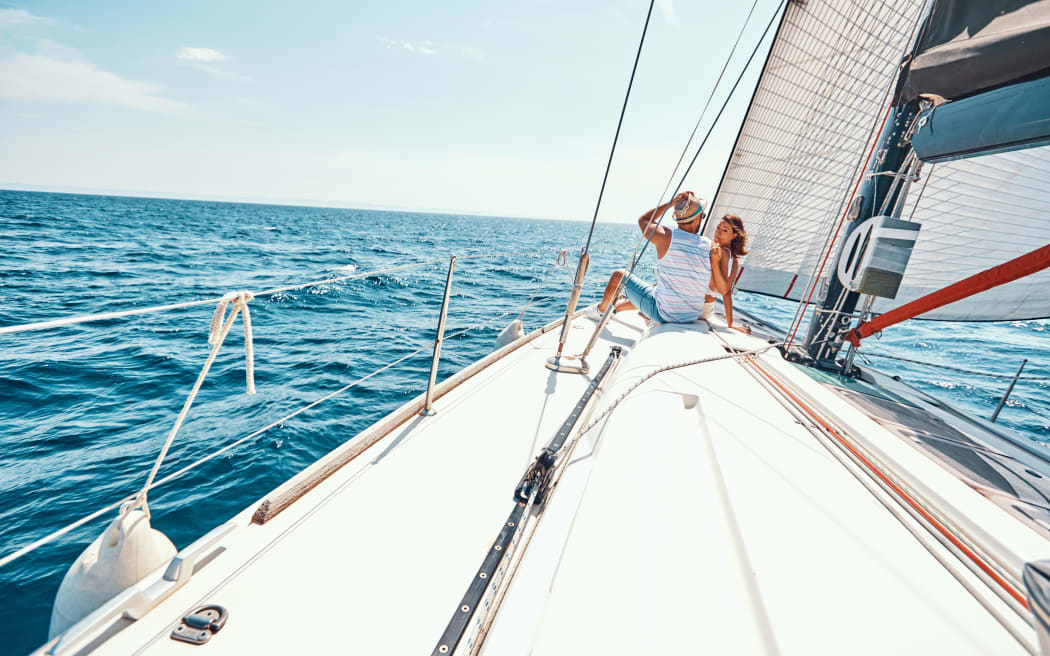 Young happy woman with man relaxing on sailboat deck on vacation