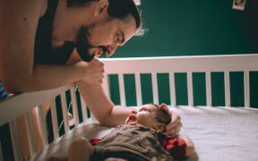 father and baby in cot