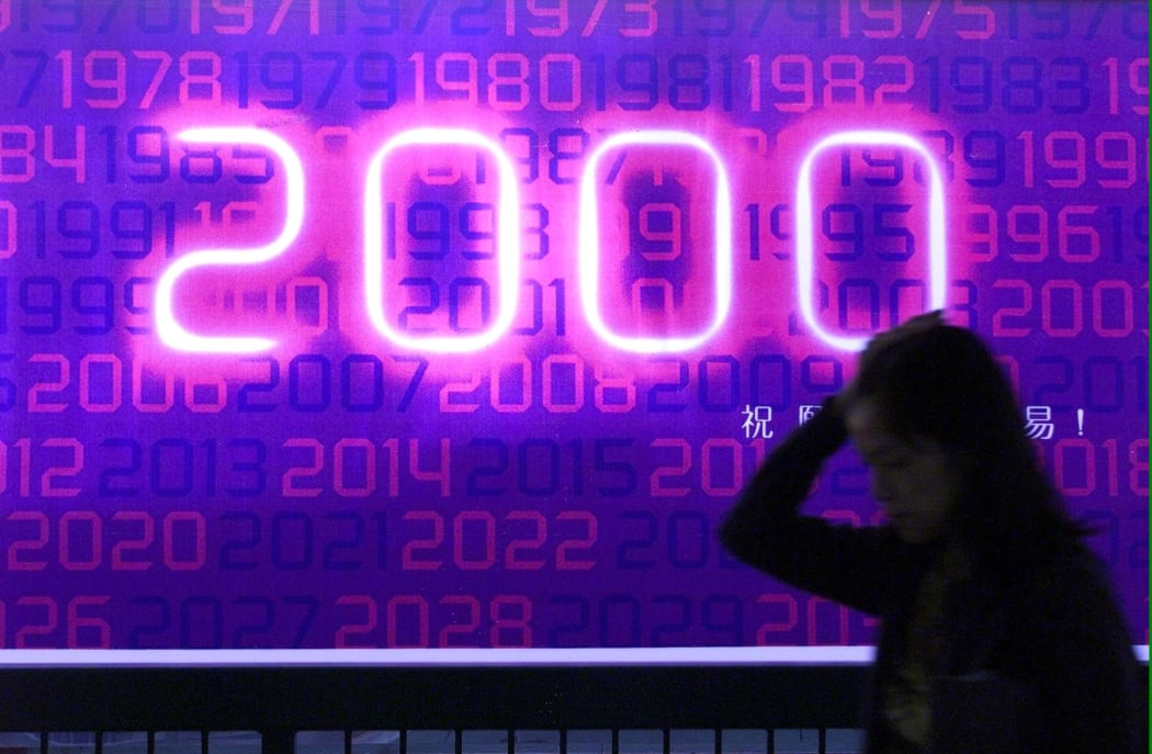 A woman walks past a billboard celebrating the coming year 2000 in Hong Kong.
