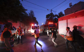 EDITORS NOTE: Graphic content / Palestinian Red Crescent rescuers rush to evacuate the wounded during clashes between Israeli troops and Palestinian gunmen in the Old City of Nablus in the northern occupied West Bank early on July 24, 2022. - Two Palestinians were killed and six others wounded overnight during an Israeli army raid on Nablus, according to the Palestinian health ministry. The Israeli army confirmed carrying out an operation in the area in a statement which said there were exchanges of fire between armed suspects and troops. (Photo by JAAFAR ASHTIYEH / AFP)