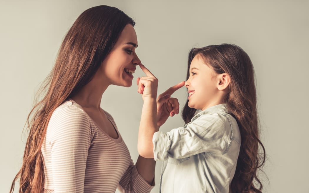 A girl and a woman touching each other's noses.