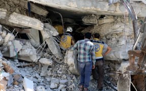 Syrian civil defense members conduct search and rescue operations at wreckage of a building after a blast in Idlib, Syria.