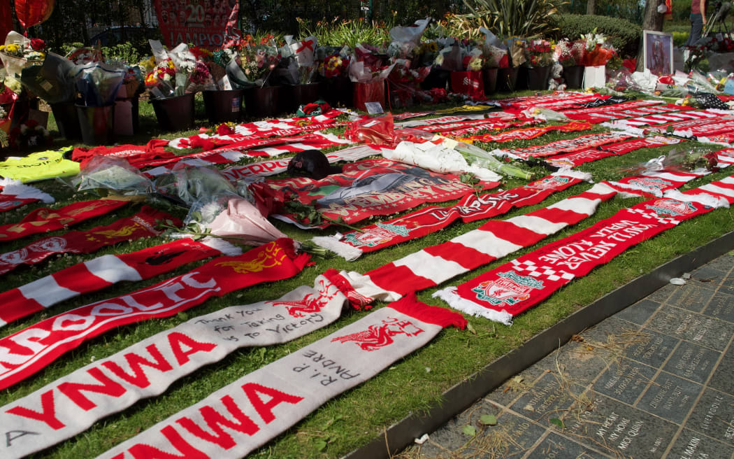 Liverpool scarves are seen beside flowers left at a memorial set up close to Anfield football ground for their Portuguese forward Diogo Jota in Liverpool, north-west England July 3, 2025. Liverpool striker Diogo Jota died along with his brother early July 3, 2025 in a road accident in northwest Spain, the Spanish Civil Guard said. The accident occurred on a highway in the province of Zamora. The vehicle "left the road" before bursting into flames, the Civil Guard said, adding that the two passengers, Diogo Jota and his brother Andre Felipe, also a professional footballer, were deceased. (Photo by Paul BARKER / AFP)