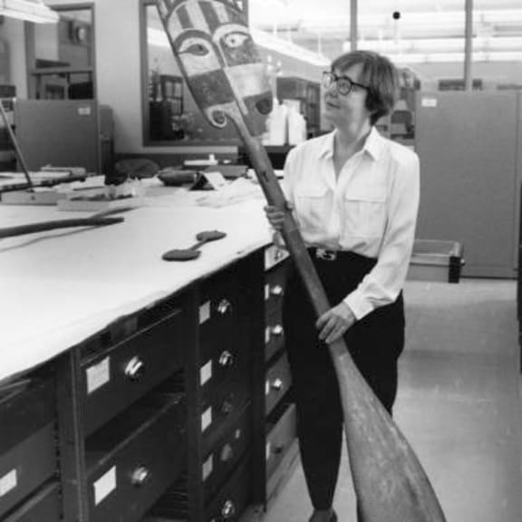 Adrienne Kaeppler holding a paddle at Smithsonian Museum.