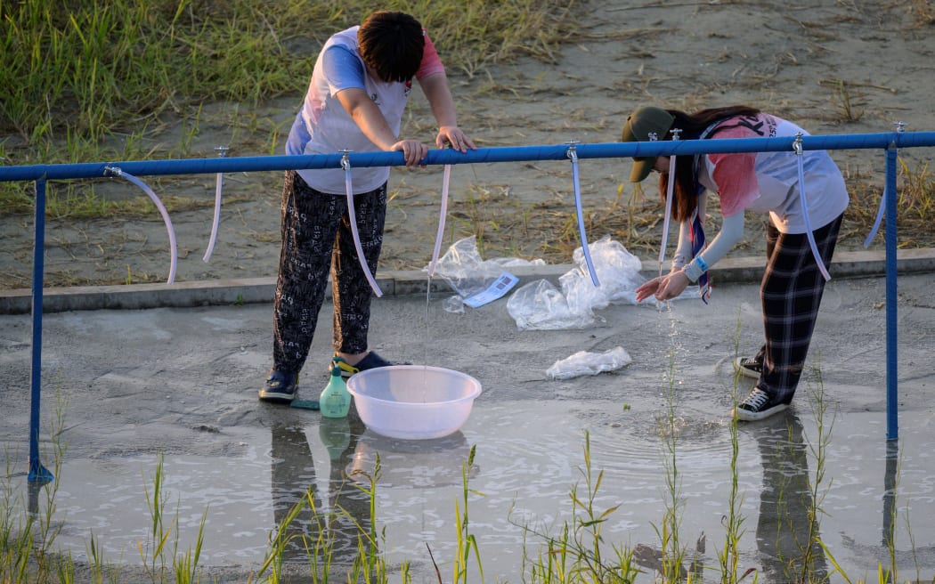 Scouts fill up containers of water at the campsite of the World Scout Jamboree in Buan, North Jeolla province on 5 August, 2023.