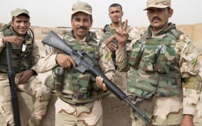 Four Iraqi soliders in full kit and armed line up for photos.