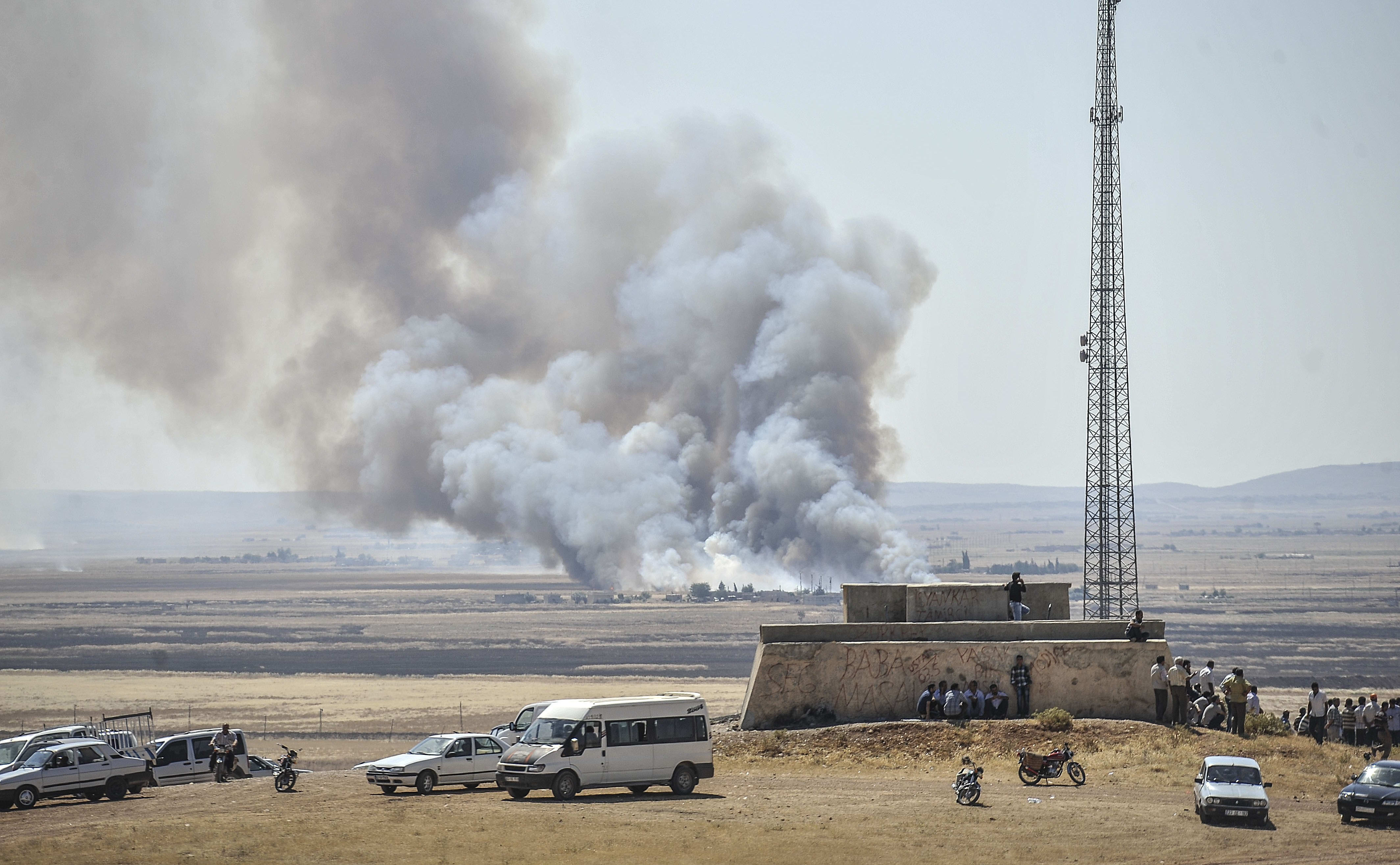 Smoke rises as Islamic State fighters and Kurdish armed groups clash in the Syria-Turkey border town of Kobane on 26 June.