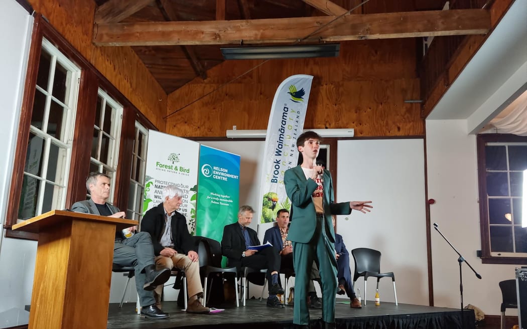 Nelson mayoral candidate Rohan O'Neal-Stevens speaking to a public meeting, with (seated from left) Matt Lawrey, Kerry Neal, Richard Osmaston, Tim Skinner and Nick Smith.