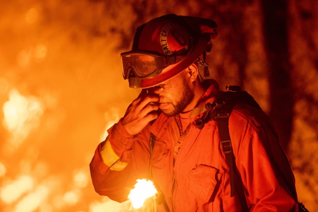 An inmate firefighter pauses during a firing operation as the Carr fire continues to burn.