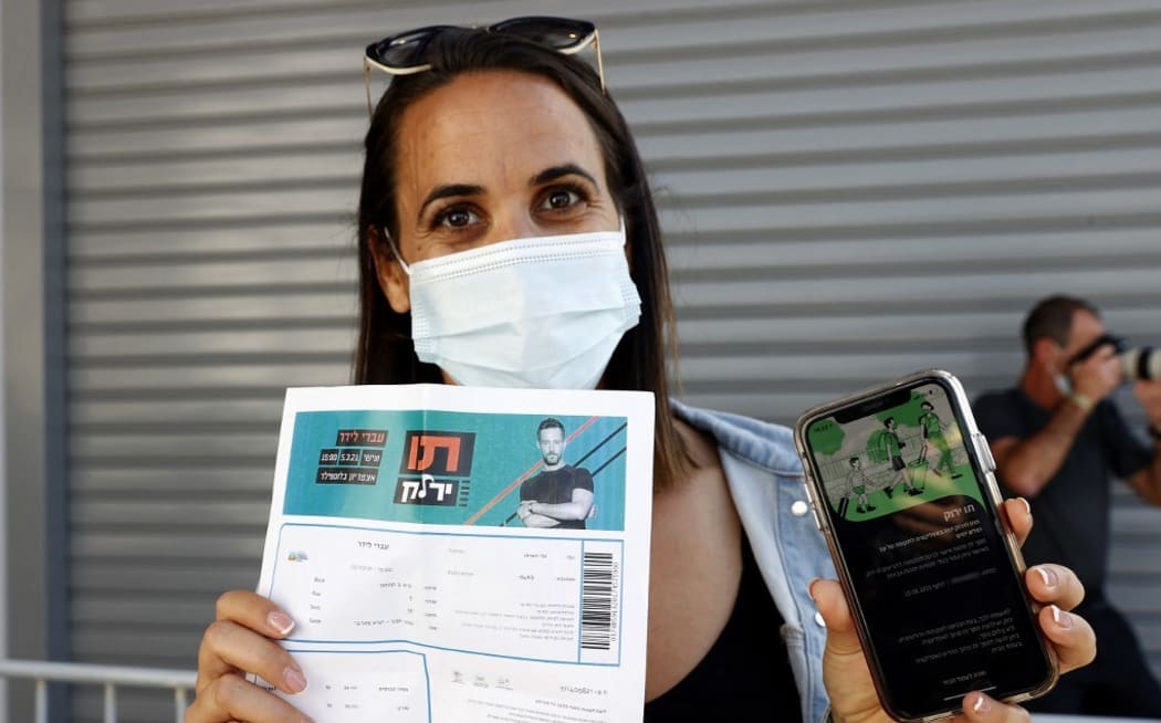 An attendee shows off a "green pass" (proof of being fully vaccinated against COVID-19 coronavirus disease) upon arrival at Bloomfield Stadium in Tel Aviv on March 5, 2021, before attending a "green pass concert" for vaccinated seniors,
