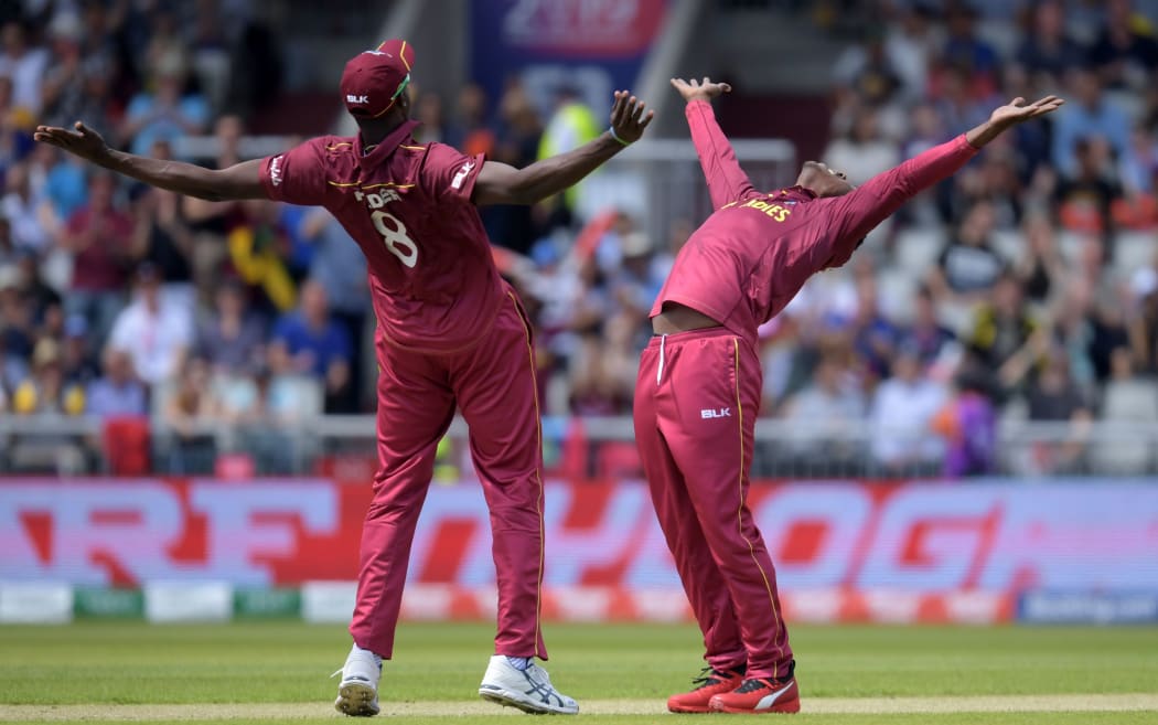 West Indies' Sheldon Cottrell (R) celebrates with West Indies' captain Jason Holder after the dismissal of New Zealand's Colin Munro during the 2019 Cricket World Cup group stage match between West Indies and New Zealand at Old Trafford in Manchester.
