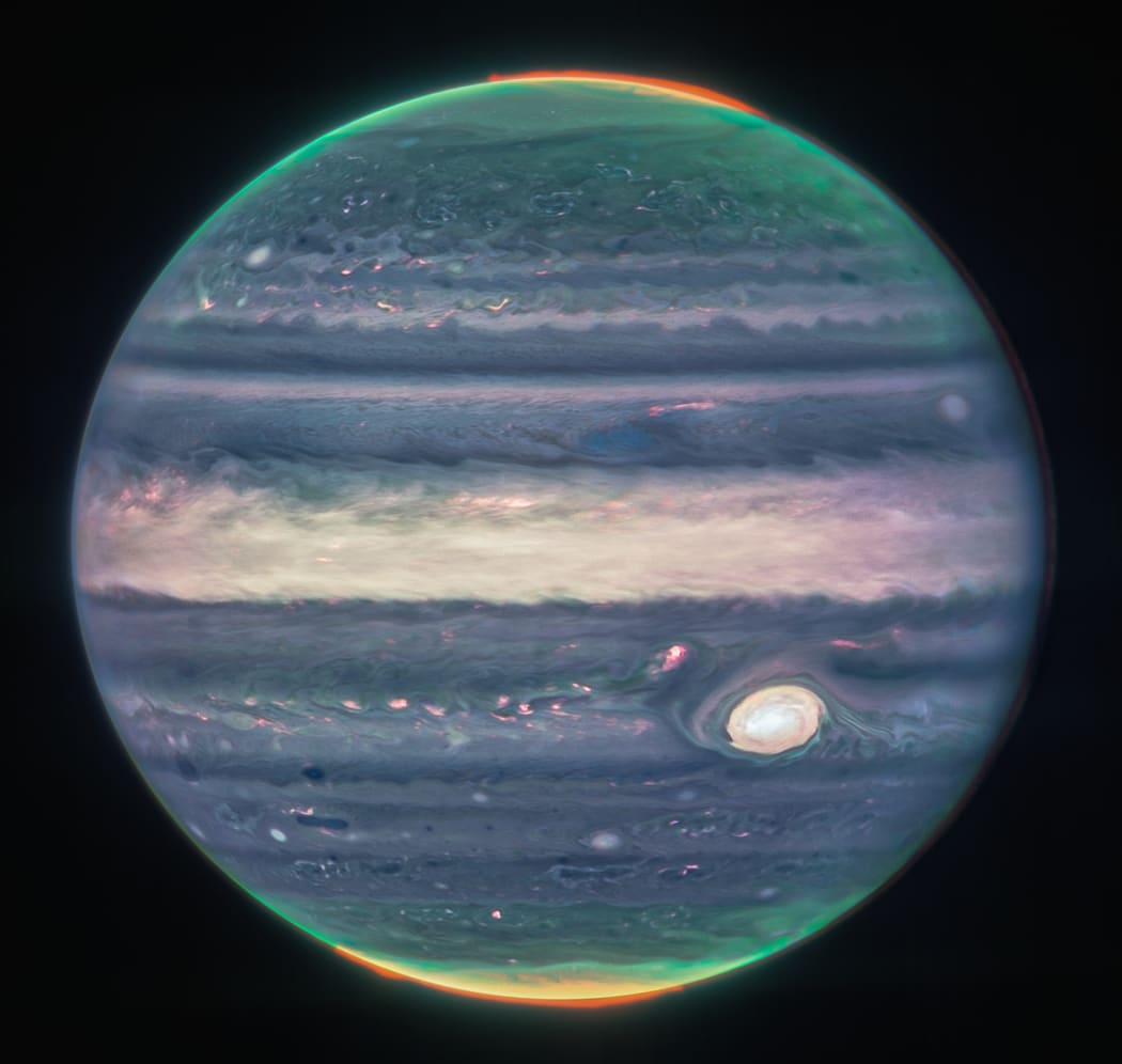 An infrared view of Jupiter from the JWST. Note the auroral glow at the poles; this is caused by the interaction of charged particles from the sun with Jupiter’s magnetic field.