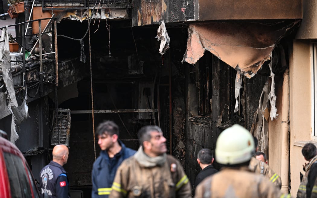 Emergency personnel intervene in front of a burnt residential building after a fire broke out, in Istanbul on April 2, 2024. A fire killed at least 29 people in a 16-storey residential building in Istanbul on April 2, the governor of Turkey's economic capital said, updating an earlier toll of 15 dead and eight hurt. The blaze had broken out during construction work in the first and second floors below ground, which housed a nightclub, governor Davut Gul told reporters. (Photo by OZAN KOSE / AFP)