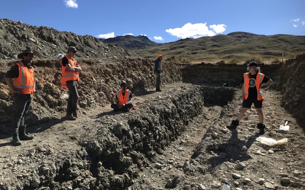 The team of geologists standing in the trench site. The large trench area is two tiered, with a narrower deeper trench within the larger wider one.