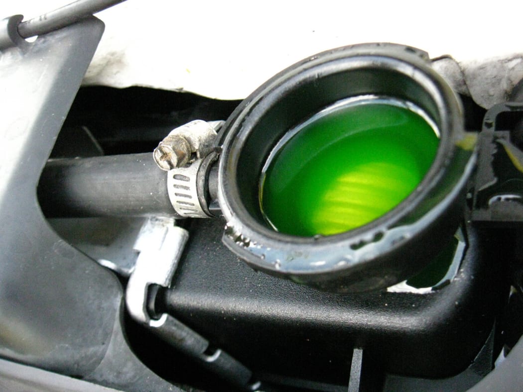 Fluorescent green-dyed antifreeze is visible in the radiator header tank when car radiator cap is removed