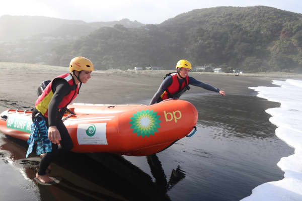 Max Walton-Hannay, 15, (right) and Illinois Cooney, 17, pull an inflatable rescue boat into the water at Piha on Auckland's West Coast.
