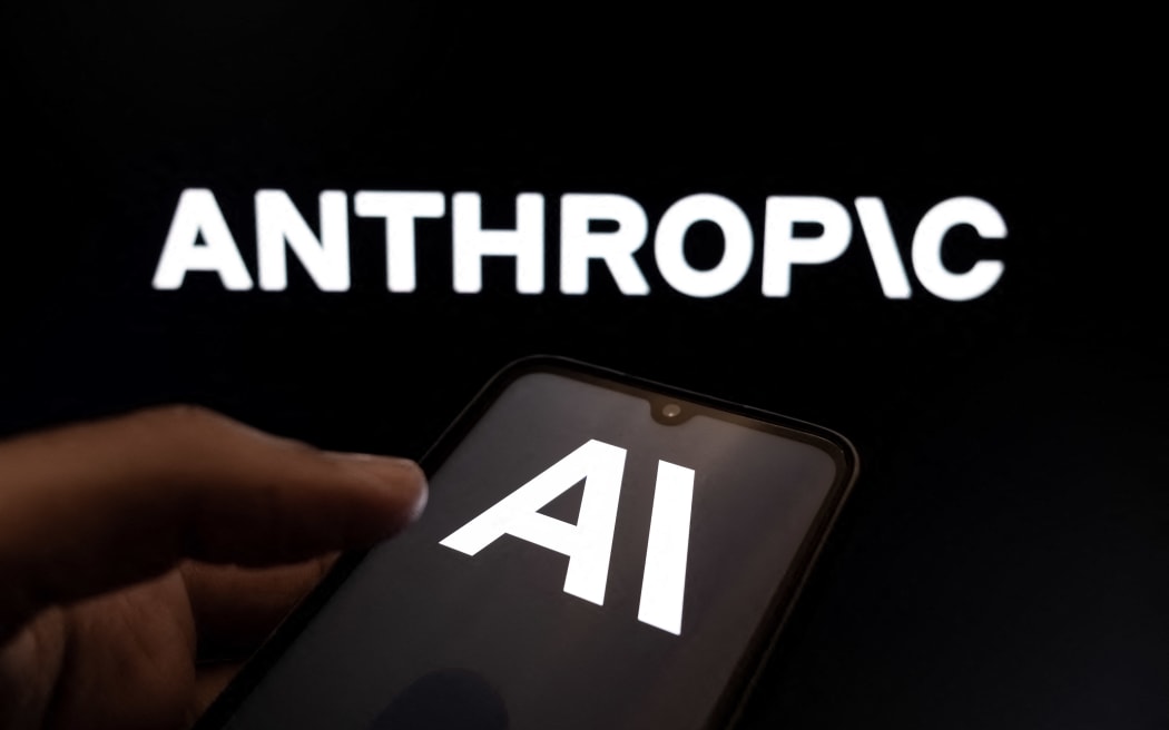 The Anthropic AI logo appears on a smartphone screen and as the background on a laptop computer screen in this photo illustration in Athens, Greece, on February 24, 2026. (Photo by Nikolas Kokovlis/NurPhoto) (Photo by Nikolas Kokovlis / NurPhoto via AFP)